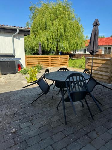 a table and chairs and an umbrella on a patio at Bøtø strand ferielejlighed 5 in Marielyst