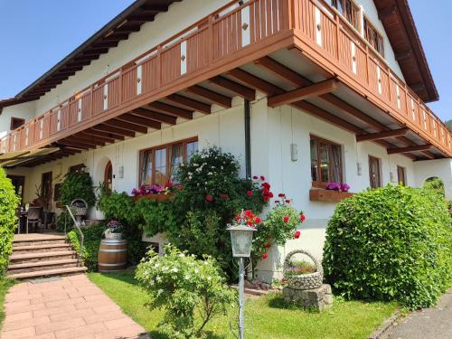 a house with a balcony and flowers in the yard at Landhaus Mast in Baiersbronn