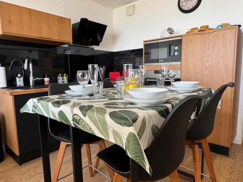 - une table avec des assiettes et des verres dans la cuisine dans l'établissement Fabuleux Face Mer 9ème étage, à Saint-Jean-de-Monts