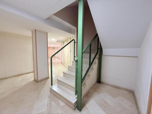 a staircase in a house with a green railing at Encantador Ático a 2,6 km de la Playa in San Juan de Alicante