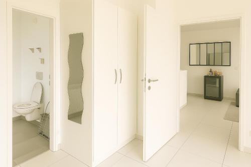 La salle de bains est pourvue de murs blancs et de toilettes. dans l'établissement Thanh Ho entre Disneyland et Paris-parking Gratuit, à Gournay-sur-Marne