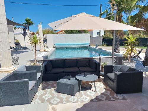 - une piscine avec un canapé, une table et un parasol dans l'établissement Villa 6 personnes piscine chauffée, à Saint-Aunès