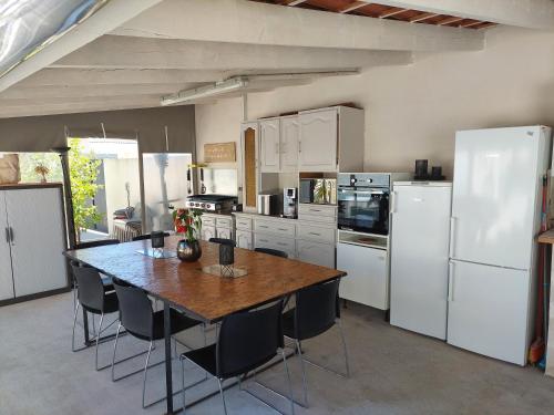 une cuisine avec une table en bois et des appareils électroménagers blancs dans l'établissement Villa 6 personnes piscine chauffée, à Saint-Aunès