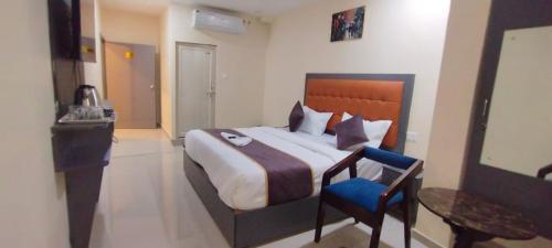 ein Schlafzimmer mit einem großen Bett und einem blauen Stuhl in der Unterkunft hotel coolriver inn in Visakhapatnam