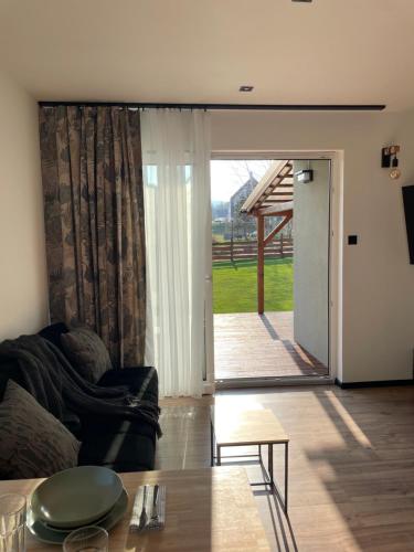 a living room with a couch and a sliding glass door at Domek Na Miodowej in Sulistrowiczki