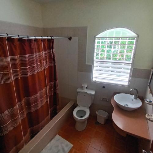 a bathroom with a toilet and a sink and a window at El jardín del coco in Las Galeras