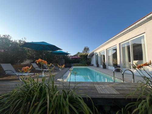 une maison avec une piscine et un parasol dans l'établissement Maison climatisée 8 personnes lege cap ferret, à Lège-Cap-Ferret