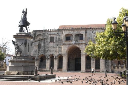 a group of pigeons in front of a building with a statue at Hotel Conde de Penalba in Santo Domingo