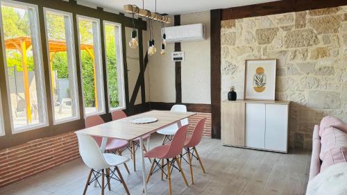 a dining room with a wooden table and pink chairs at Le Mas des Cerisiers in Le Temple-sur-Lot