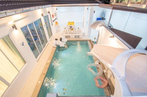 an indoor swimming pool with a slide in a house at Mina Pool Villa in Ban Huai Yai