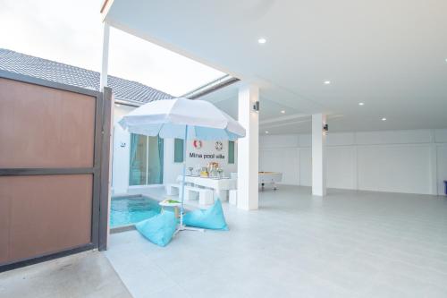 a swimming pool with an umbrella in a building at Mina Pool Villa in Ban Huai Yai