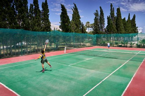 two people playing tennis on a tennis court at Nahrawess Resort & Thalasso in Hammamet