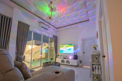 a living room with a couch and a tv at Mina Pool Villa in Ban Huai Yai