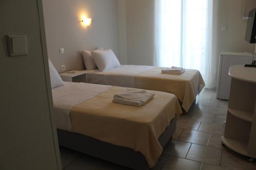 two beds in a hotel room with towels on them at Stefania rooms in Ligia