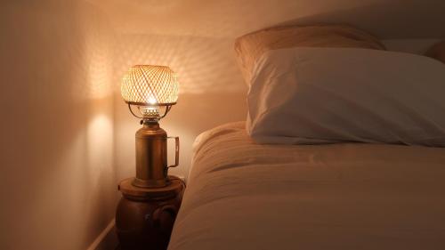 a lamp sitting next to a bed with a pillow at La Maison du Griffoul BB à Salles la Source cascade et terroir in Salles-la-Source