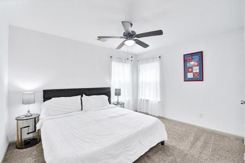 a white bedroom with a white bed and a ceiling fan at Charming accommodation in Houston! in Houston