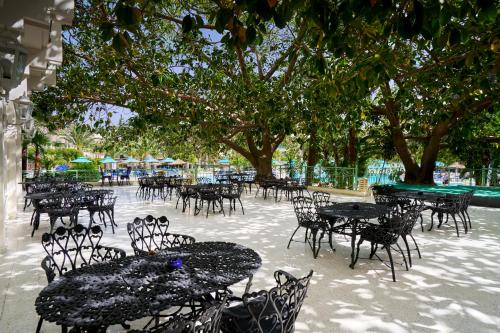 an empty patio with tables and chairs and trees at Nahrawess Resort & Thalasso in Hammamet
