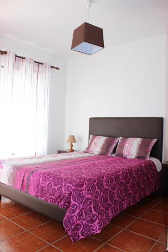 a bedroom with a purple bed with a pink bedspread at Baleal Holiday Apartment in Baleal