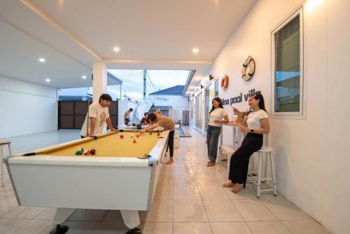 a group of people standing around a pool table at Mina Pool Villa in Ban Huai Yai
