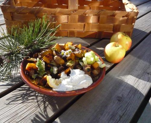 a bowl of food on a wooden table with apples at Sälstationen - The seal station 