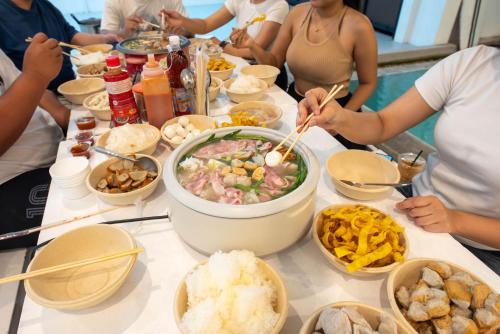 a group of people sitting around a table with food at Mina Pool Villa in Ban Huai Yai