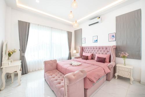 a pink bedroom with a pink bed and a couch at Mina Pool Villa in Ban Huai Yai