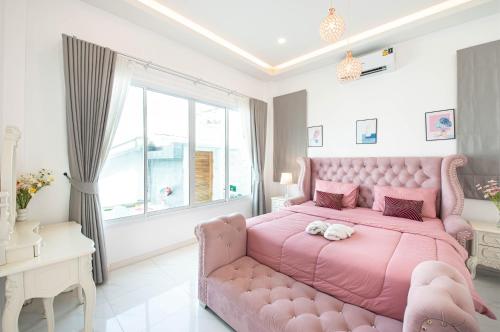 a pink bed in a room with a pink couch at Mina Pool Villa in Ban Huai Yai