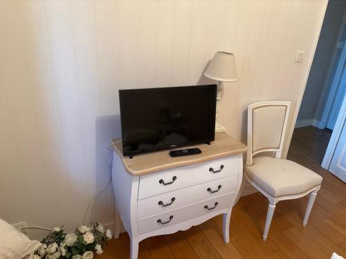 une chambre avec une commode sur laquelle se trouve une télévision dans l'établissement La mancelle, au Mans