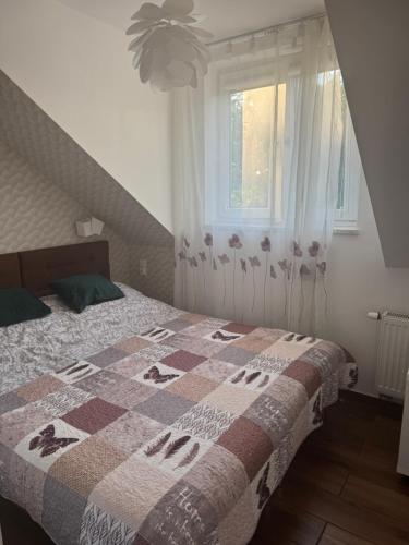 a bedroom with a bed with a quilt on it at Pensjonat E&M in Mikołajki