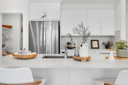 a kitchen with white cabinets and a stainless steel refrigerator at Luxury AC Sleeps 7 in Edmonton
