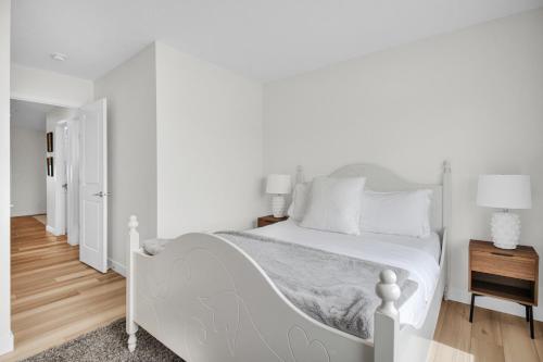 a white bedroom with a white bed and wooden floors at Luxury AC Sleeps 7 in Edmonton