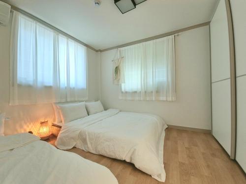 a bedroom with two beds and a window at 경주스테이구황,주차2대,스텐바이미,마샬스피커,다이슨에어랩,황리단길과 경주월드 관광에 위치 최상 in Gyeongju