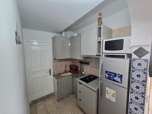 a small kitchen with a refrigerator and a microwave at Sayda Appart Hotel in Chebba