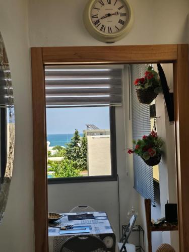 a clock on the wall above a window with a view of the ocean at Sayda Appart Hotel in Chebba