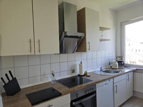 a kitchen with white cabinets and a sink and a window at Appartment am Yachthafen in Bremerhaven