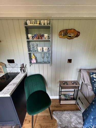 a living room with a green chair and a table at Forest view shepherds hut Hare hut in Ewhurst