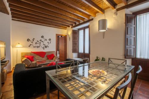 ein Wohnzimmer mit einem Sofa und einem Glastisch in der Unterkunft Casa Montalbán Apartamentos Turísticos in Granada