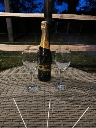 a bottle of champagne and two wine glasses on a table at Forest view shepherds hut Hare hut in Ewhurst