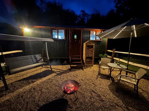 a backyard with a fire pit and a house at Forest view shepherds hut Hare hut in Ewhurst