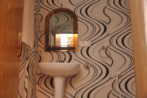 a bathroom with a sink and a mirror on a wall at Purasanda Villa in Sigiriya