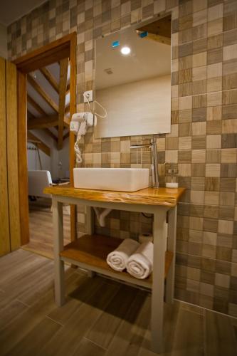 a bathroom with a sink and a mirror and towels at Guest House 10 de Agosto in Figueira da Foz
