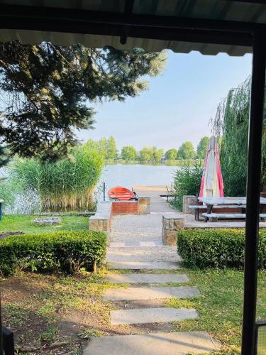 a stone path leading to a lake with a boat at Viktória Apartman DunaWeekend in Makád