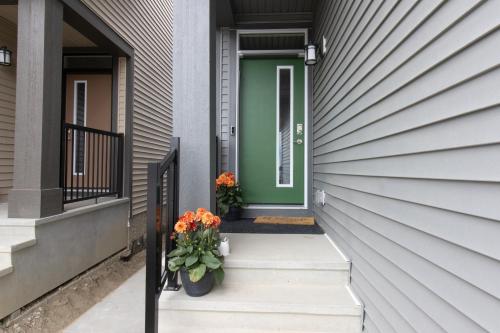 a green door on a house with flowers on the steps at Luxury AC Sleeps 7 in Edmonton