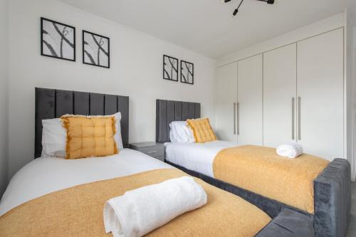 two beds in a room with white and orange at Luxury 2 bed house in Dartford, United Kingdom in Dartford