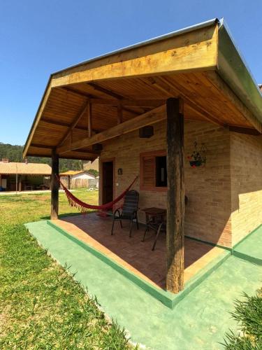 a pavilion with a table and chairs in a field at Chalés Bons Ventos in São Bento do Sapucaí