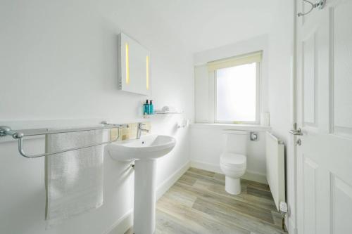 a white bathroom with a sink and a toilet at Taypark River View Apartment in Dundee