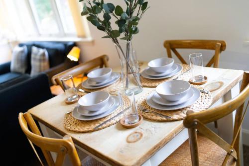 a wooden table with plates and glasses and a vase with flowers at Taypark River View Apartment in Dundee