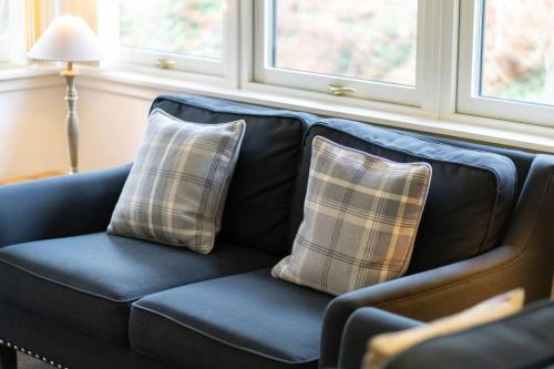 a blue couch with two plaid pillows on it at Taypark River View Apartment in Dundee