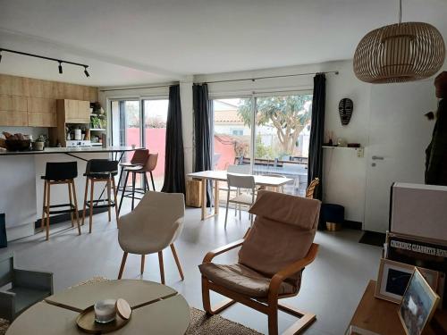 un salon avec des chaises et une table et une cuisine dans l'établissement Quiet house with wooded garden, à Les Sables-dʼOlonne