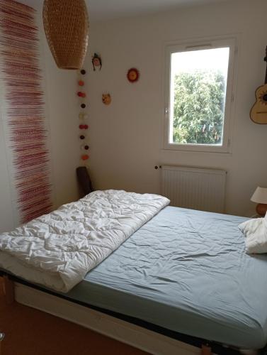 un lit dans une chambre avec une fenêtre dans l'établissement Quiet house with wooded garden, à Les Sables-dʼOlonne